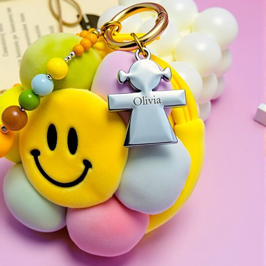 Custom name detail on smiley sunflower plush bag charm—engraved metal tag “Olivia” with gold ring and beaded strap (personalized bag charm, bagcharms)