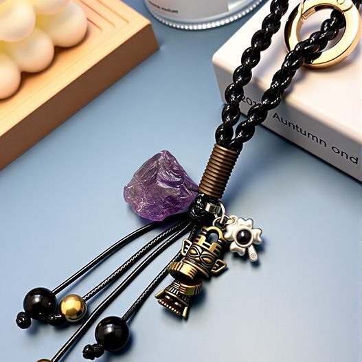 Close-up of travel bronze totem bag charm with raw amethyst, obsidian beads and braided black strap—protective travel accessory (bagcharms)