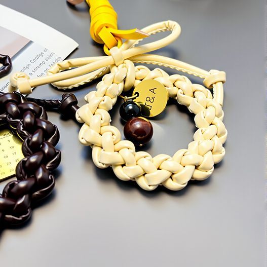 Cream leather wreath bag charm with bow, initials tag “J&A,” Tiger’s Eye and Obsidian beads on yellow strap—romantic couple accessory (bagcharms)