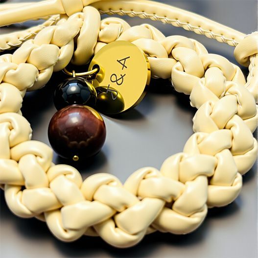 Close-up of cream handwoven leather wreath bag charm with Tiger’s Eye and Obsidian beads plus personalized initials gold disc (bagcharms)