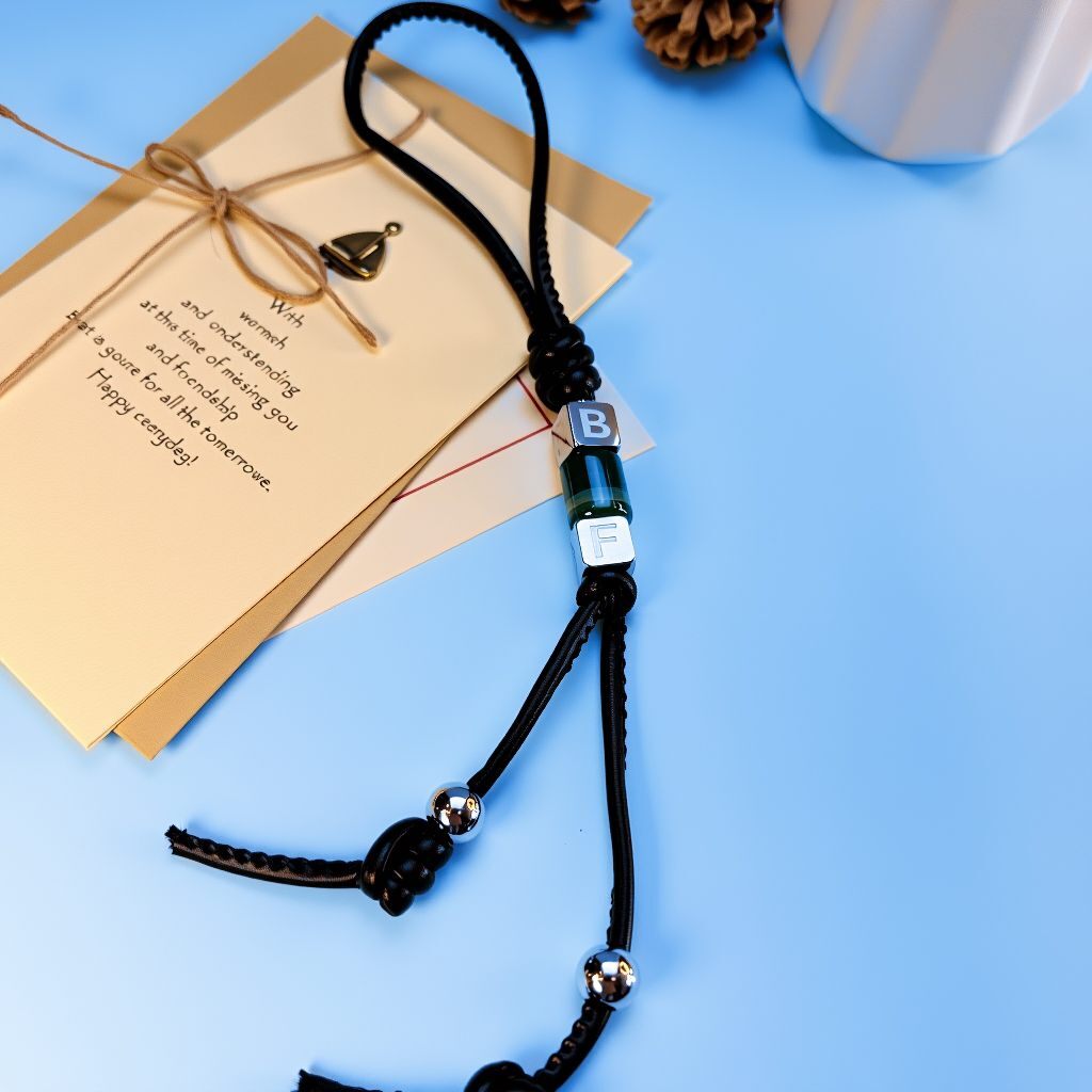 Custom letter bead bag charm showing full length cord with metal end beads and malachite energy tube