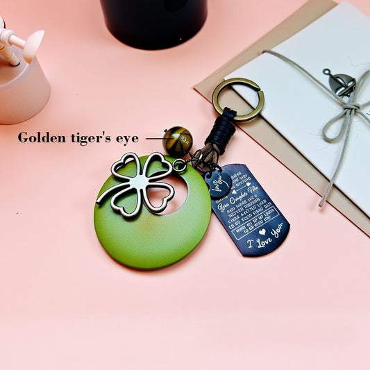 Handmade lucky four leaf clover bag charm with natural tiger's eye bead, custom engraved metal tag, and handcrafted leather strap, personalized gift accessory for good luck and protection