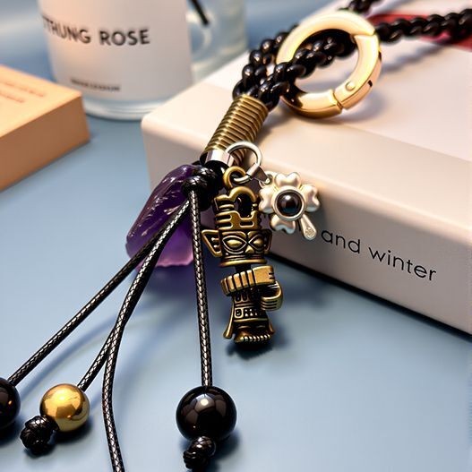 Gold ring and braided cord with bronze totem, raw amethyst and eye charm—travel souvenir bag charm detail shot (bagcharms)