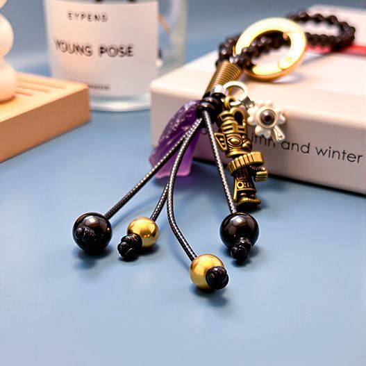 Side view of tassels on travel bronze totem bag charm—obsidian and copper beads on black cords for lucky travel vibes (bagcharms)