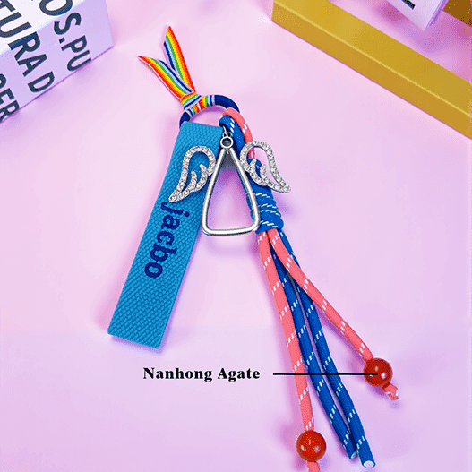 Full view of angel wing custom name backpack charm showing pink and blue paracord tassels finished with red agate beads