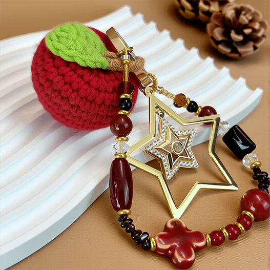 Apple-themed Christmas purse charm with layered star pendant and mixed gemstones on a wavy display prop.