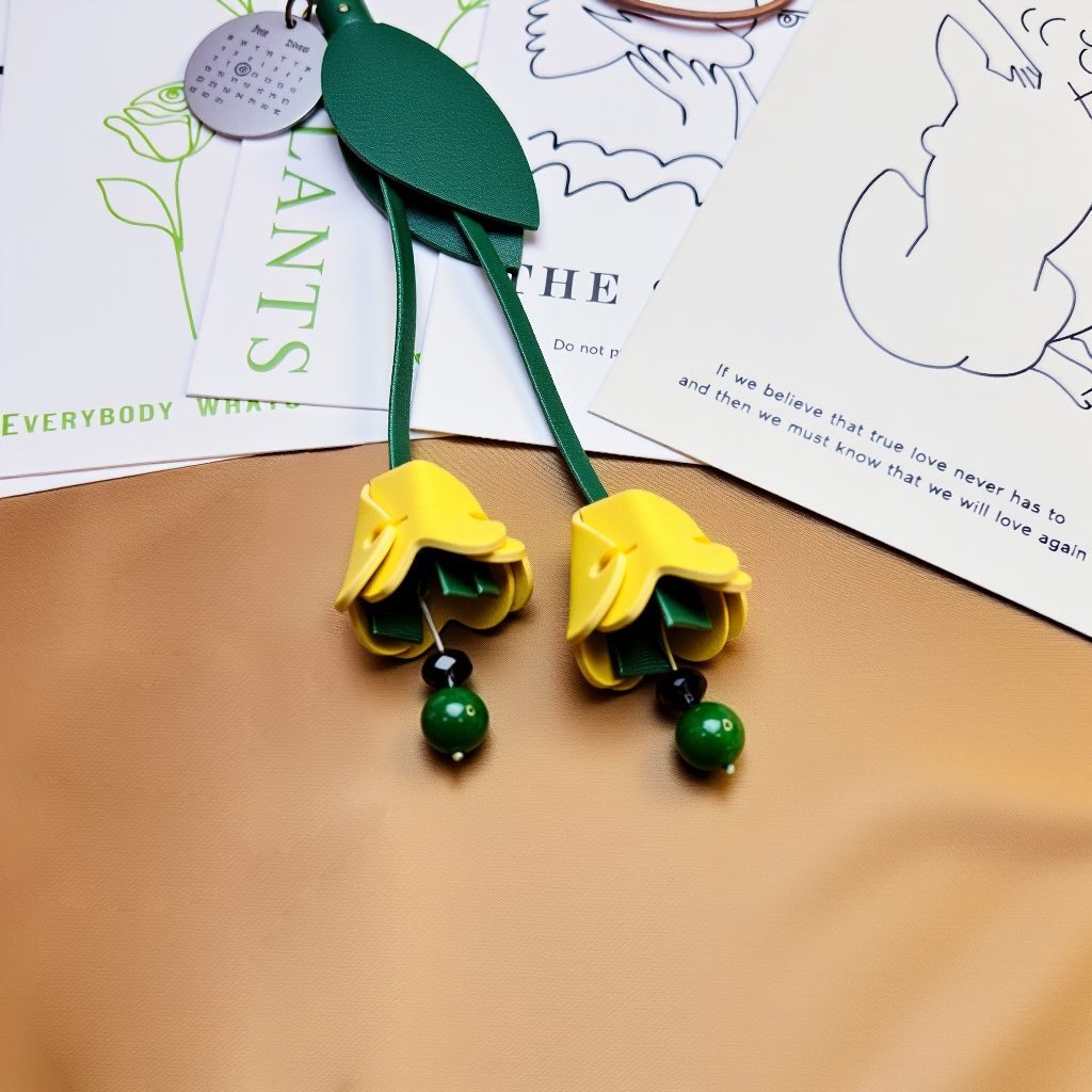 Close-up of two yellow leather tulip flowers with green agate tips on a tan surface.